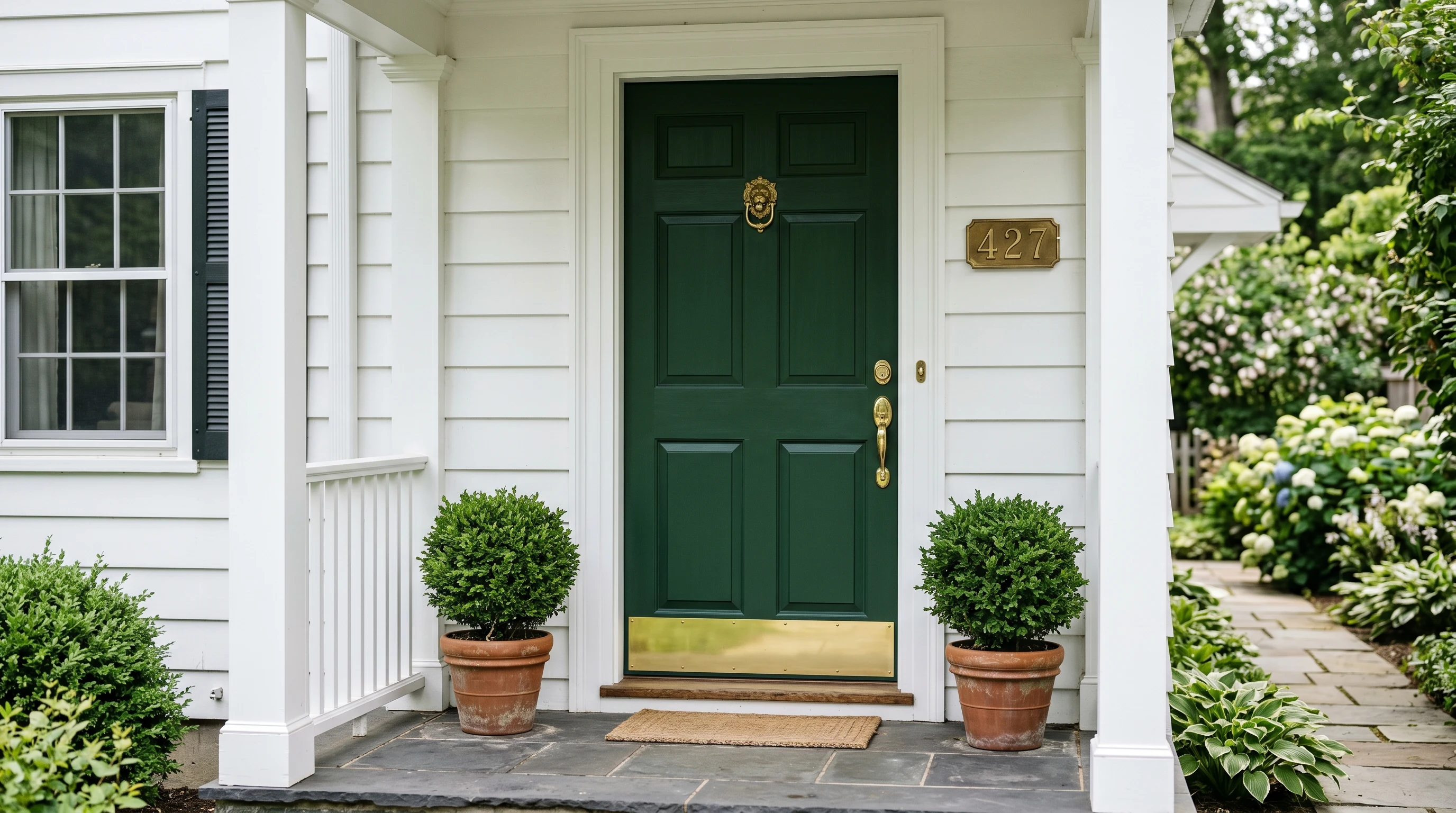 Freshly repainted forest-green exterior door on a colonial porch in clean late-morning light, brass hardware reinstalled