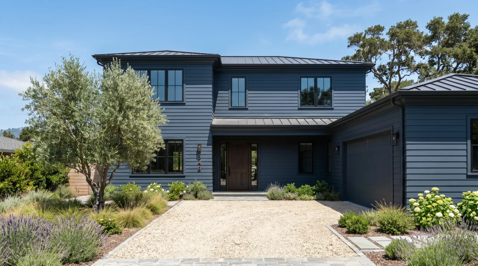 Two-story home with freshly painted deep charcoal-blue south-facing siding under hard midday summer sun