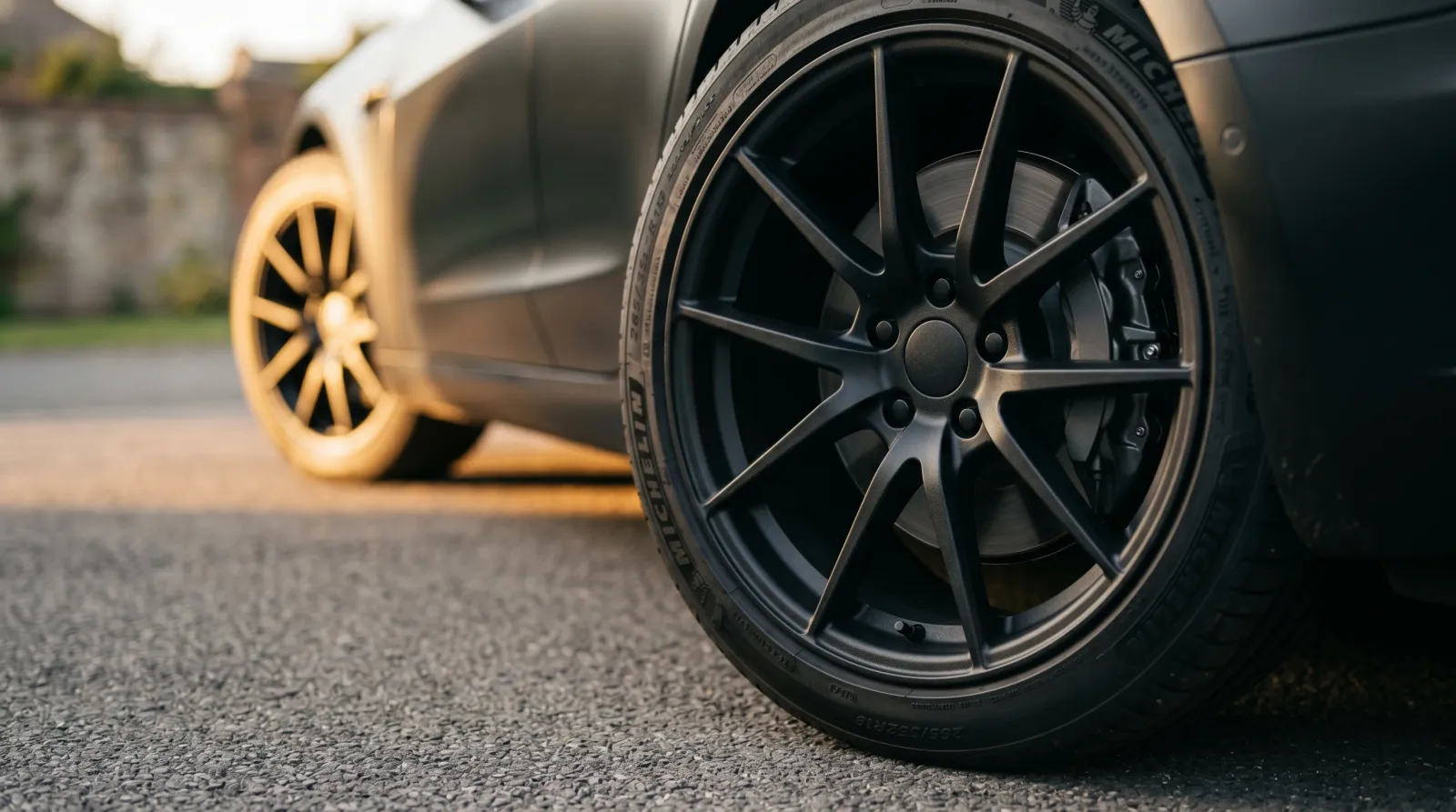 Car wheel rim freshly finished in matte black in low evening light on a clean driveway