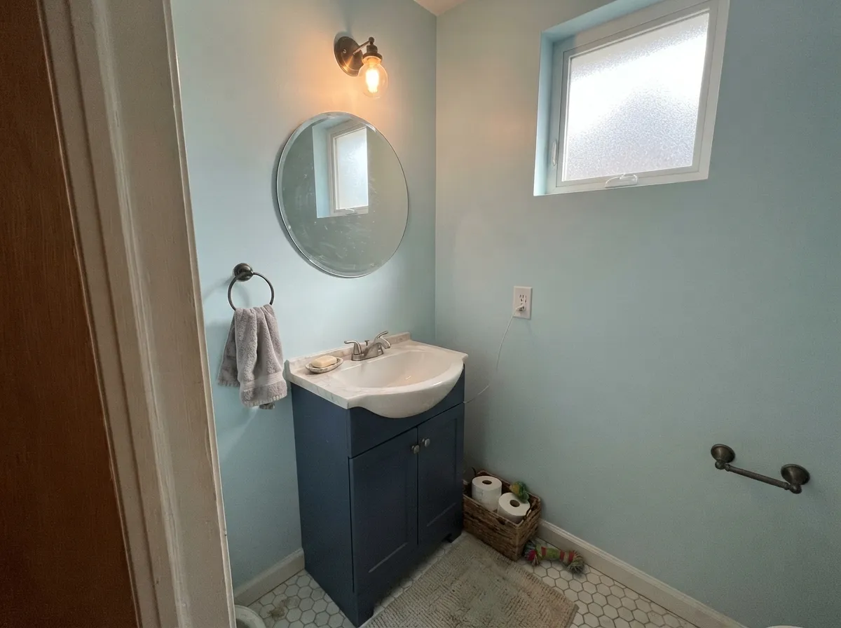 In a small bathroom the pale color can cover every wall without going flat — a navy vanity gives it the anchor it needs.