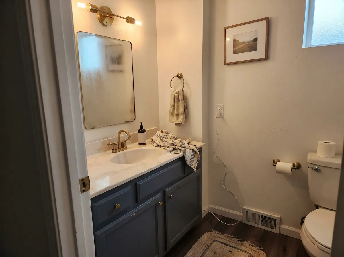 Under warm evening light the vanity settles into a soft charcoal-navy — cozy, not cold.