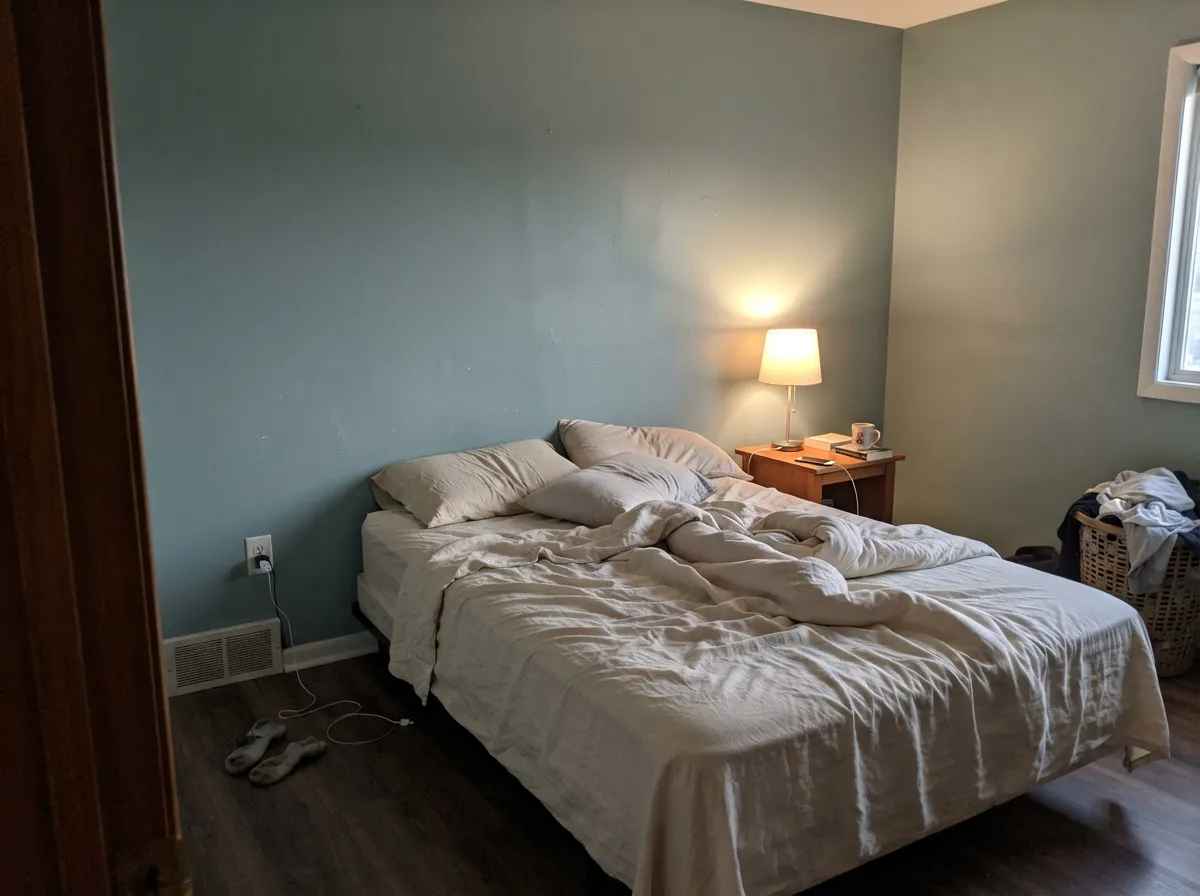 Under a warm 2700K lamp at night it settles into a muted, cozy sage — the quiet-bedroom case for this color.