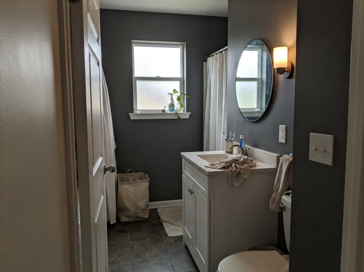 The consultant move: Cinder in a white-cabinet bath — dramatic edge, still gray, the white millwork keeping LRV 23 from going cave.