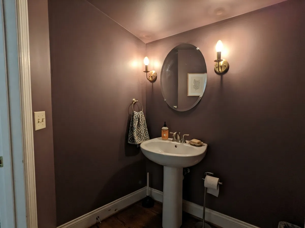 Walls and ceiling in one color under warm sconces: the darkness reads deliberate instead of accidental.