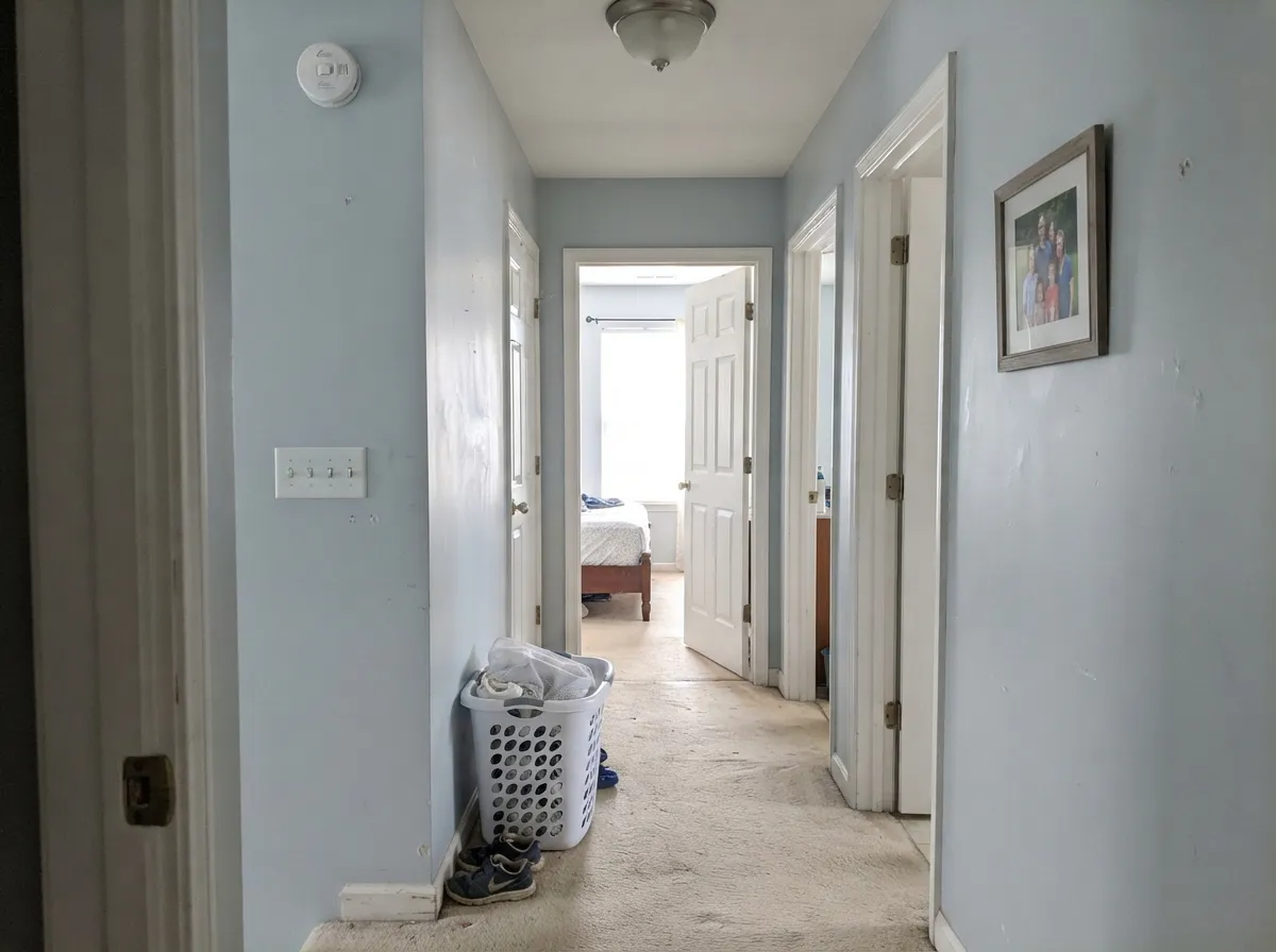 Carried down the hall from the stairs, the cool gray stays quiet enough to pass four doorways without fighting the rooms behind them.