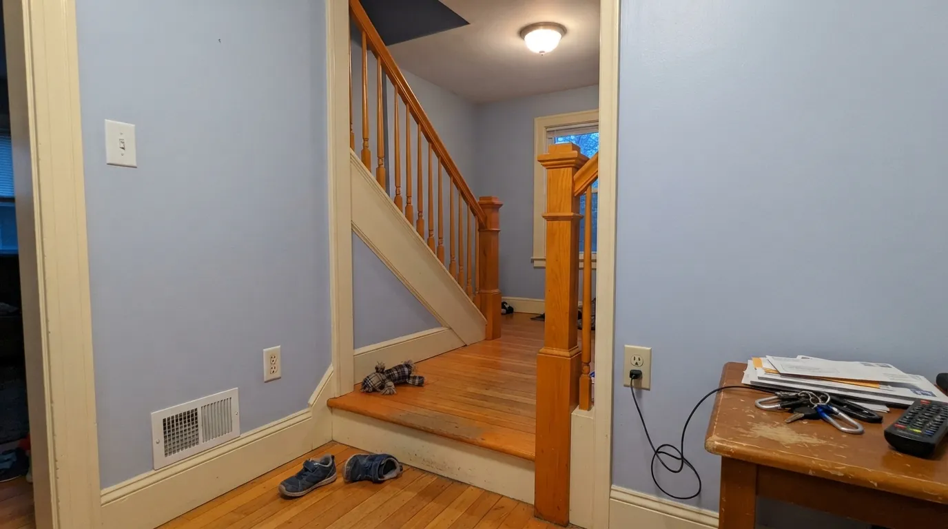 The honest shot: honey oak treads, an orange railing and cream trim push Feather Gray straight into periwinkle — the clash behind most of its bad reviews.