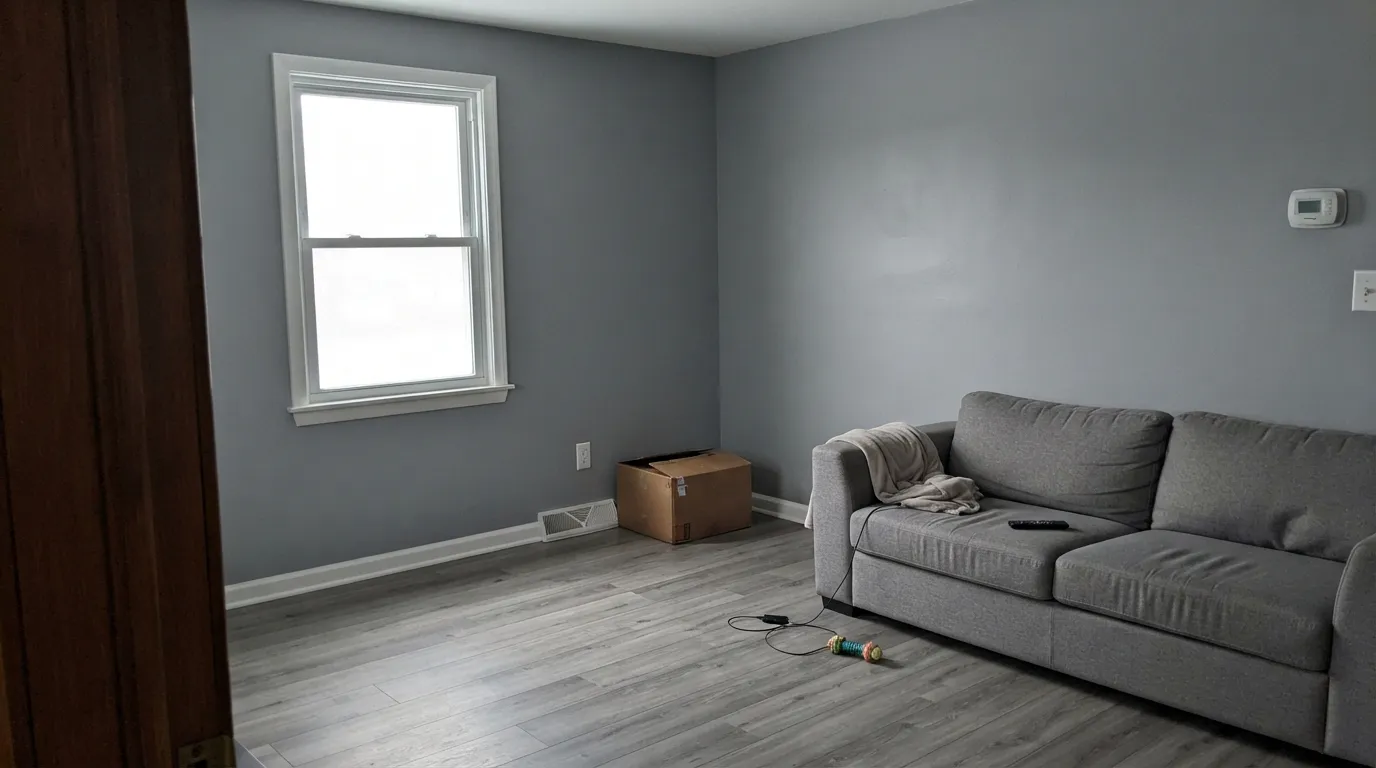 The honest shot: gray walls, gray floor, white trim and nothing warm in the room — this is the office-corridor read people complain about, and it is the room's fault, not the paint's.