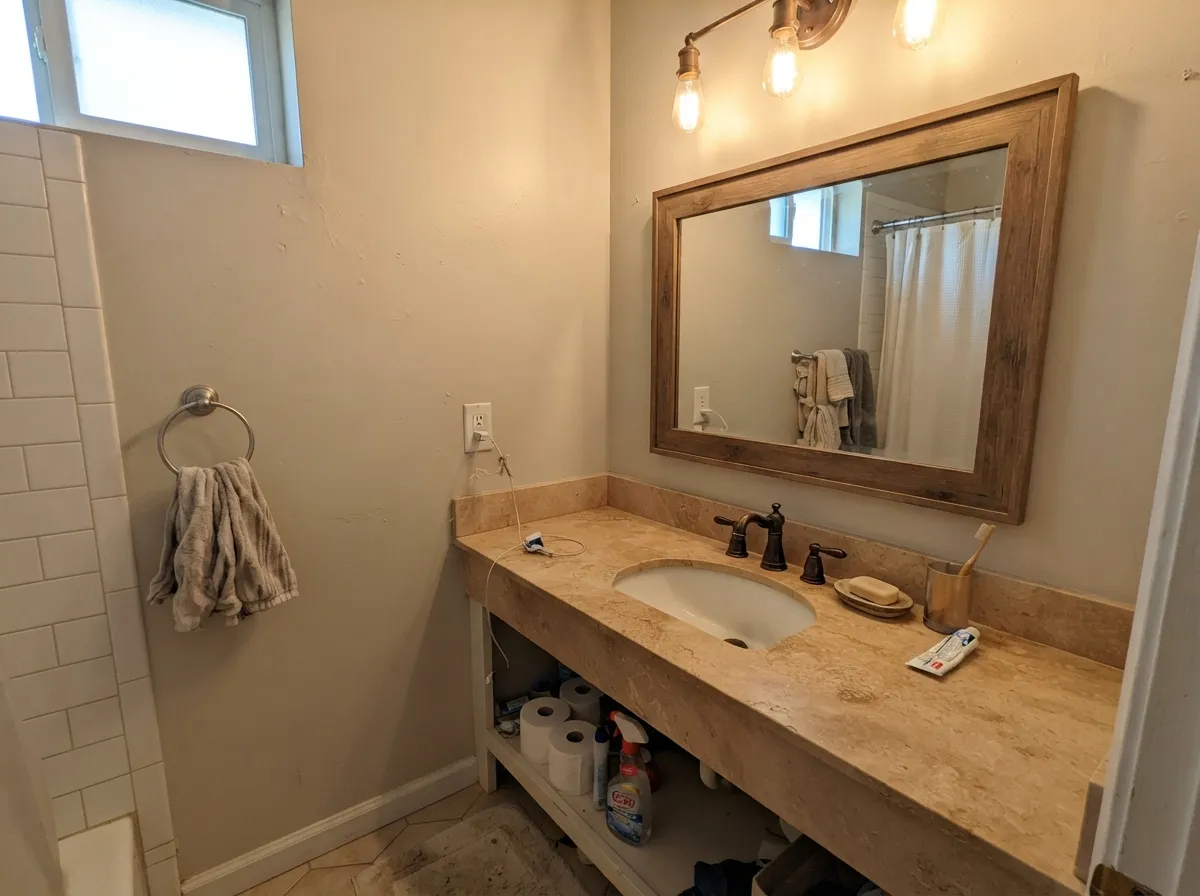 Pale Oak bathroom walls with warm stone counter under warm bulb light.