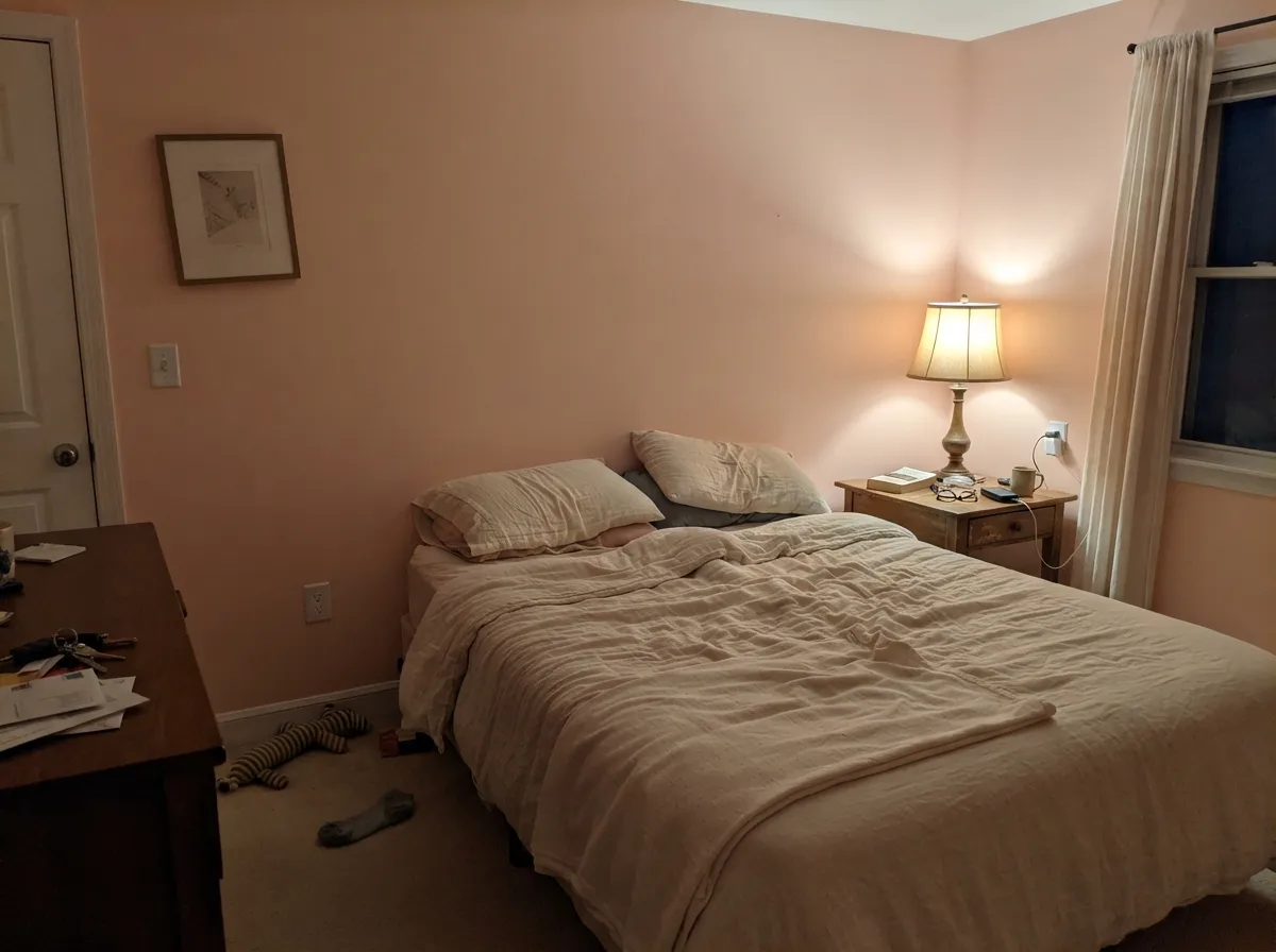 Same paint after dark under a warm 2700K lamp — the peach-pink undertone comes forward and the room turns cozy instead of neutral.