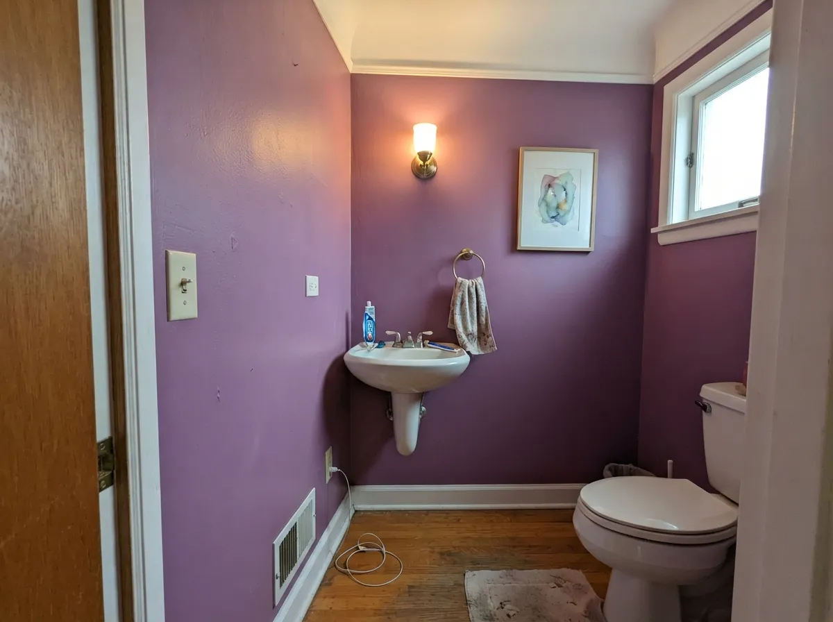 The jewel-box use: a powder room drenched in Cabaret under one warm sconce — LRV 14 is a feature when the room is this small.