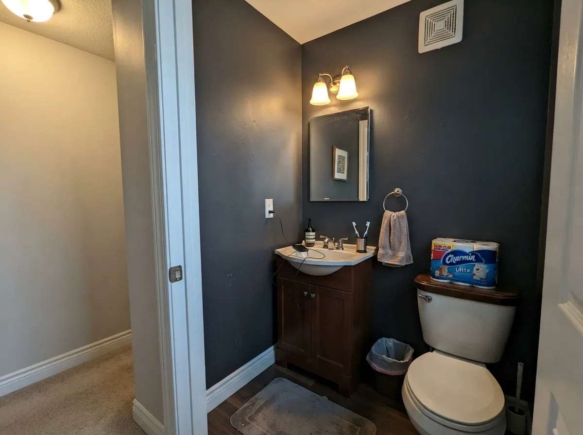 A drenched powder room with strong lighting — LRV 5 works in a small room when the sconces actually do their job and Whisper keeps the trim readable.