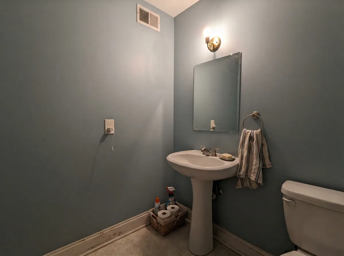 A drenched powder room: small walls take the LRV 41 blue-gray well, and one warm sconce keeps the aqua from going institutional.