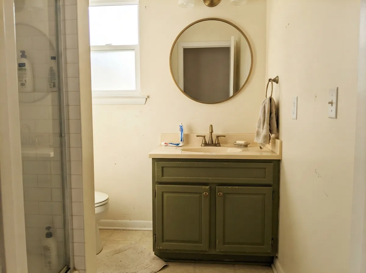A single vanity is the low-commitment way in — brass and a warm-white counter keep it feeling curated, not dark.
