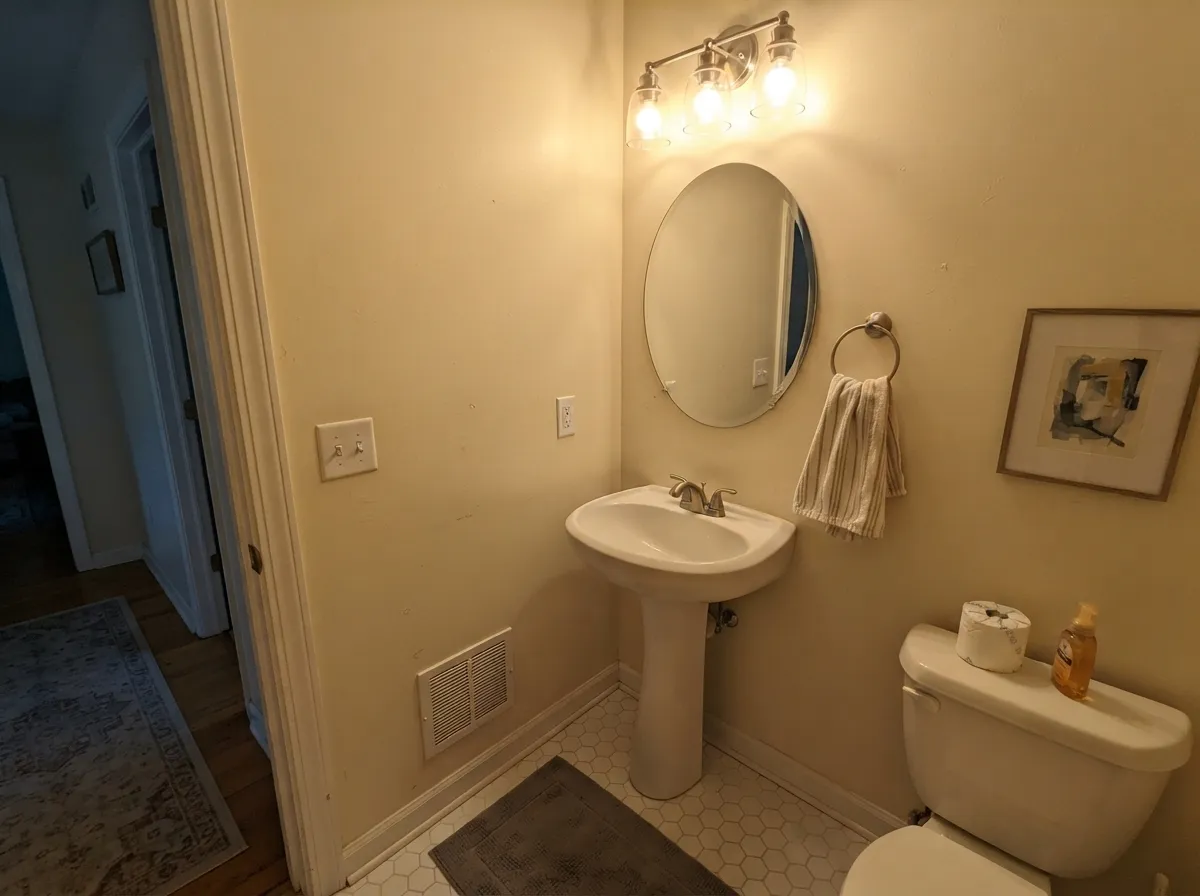 Creamy walls in a small windowless powder room with a matching vanity.