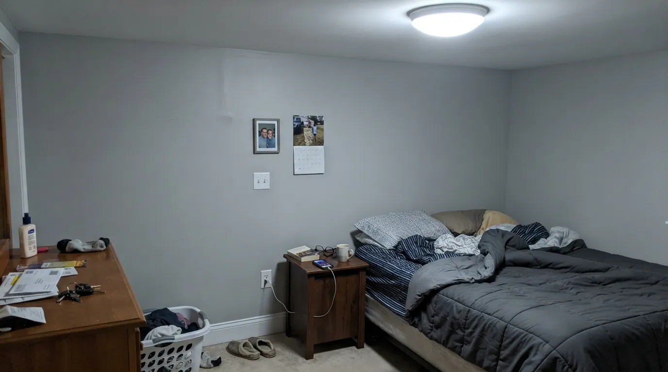 The honest shot: under a cool LED at night the green disappears completely and the wall reads plain, flat gray — the exact bulb swap this color needs.