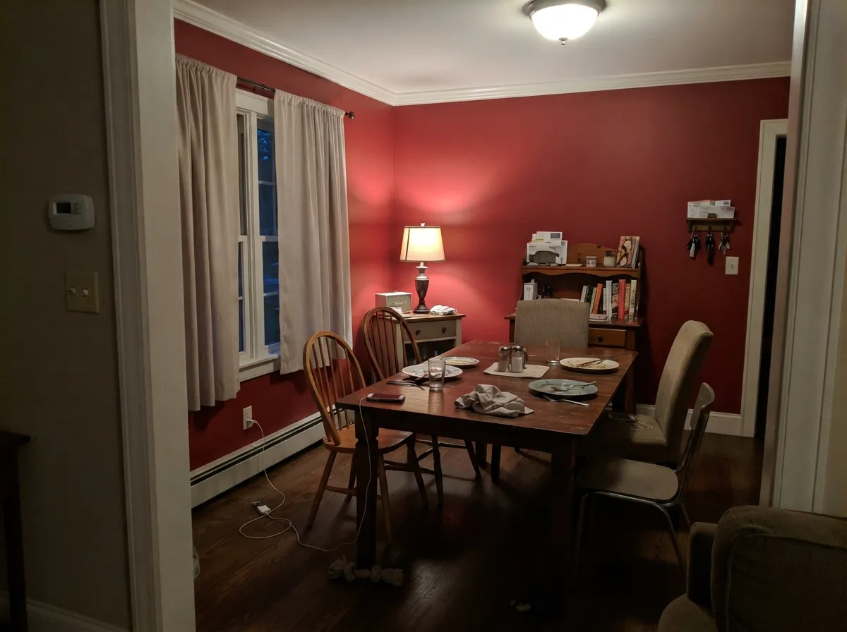 Under warm evening bulbs the red deepens toward wine — the supper-club look that makes a dining room its best interior use.