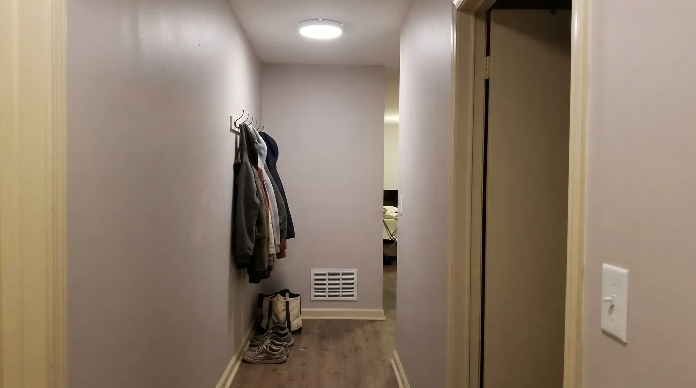 The honest shot: cream trim under cool overhead light. The yellow in the trim fights the violet in the wall, and the greige reads muddy instead of calm — the pairing mistake behind most of the complaints about this color.