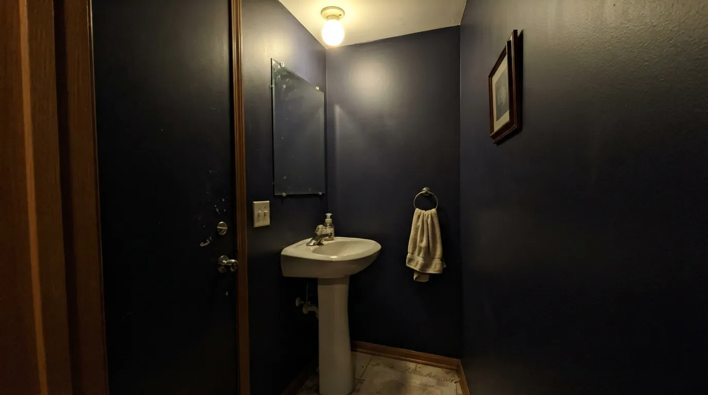 The honest shot: no window, no real fixture — at LRV 8 the blue disappears into near-black. This is the room where readers say it "just looks like a hole."