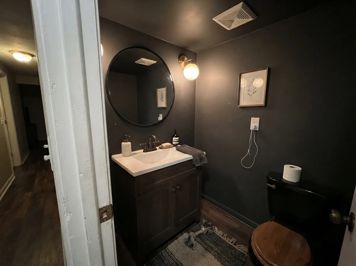 Iron Ore powder room walls and ceiling with a large mirror and warm sconce light.