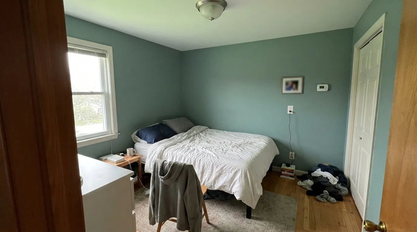The honest shot: four walls in a dim north room with no lamps, and the fresh jade collapses into a murky gray-teal that tints the ceiling and the bedding green.