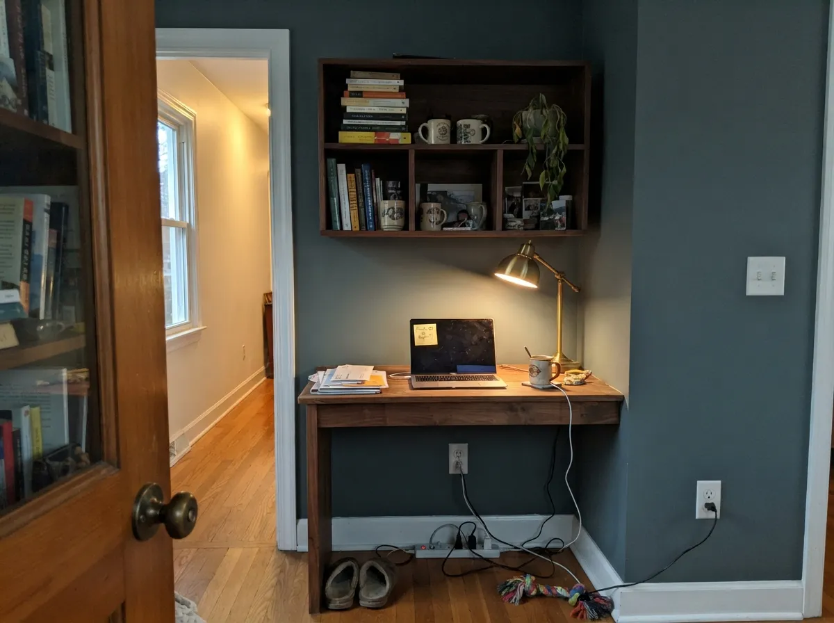With walnut and a warm lamp it settles into a calm, professional backdrop — the color's natural habitat after dark.