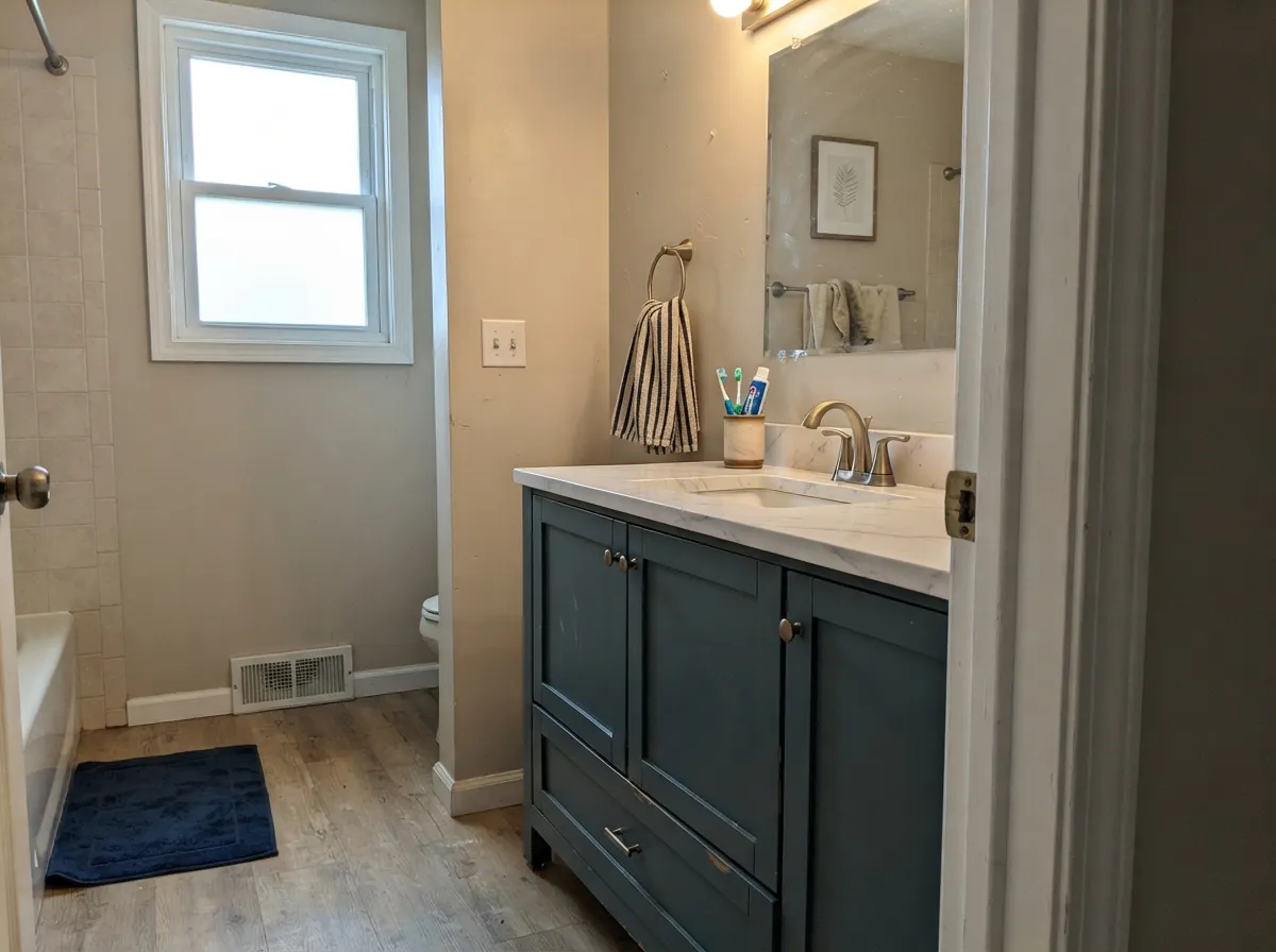 The designer move: one vanity in Still Water under a white counter, brass fixtures doing the rest of the work.