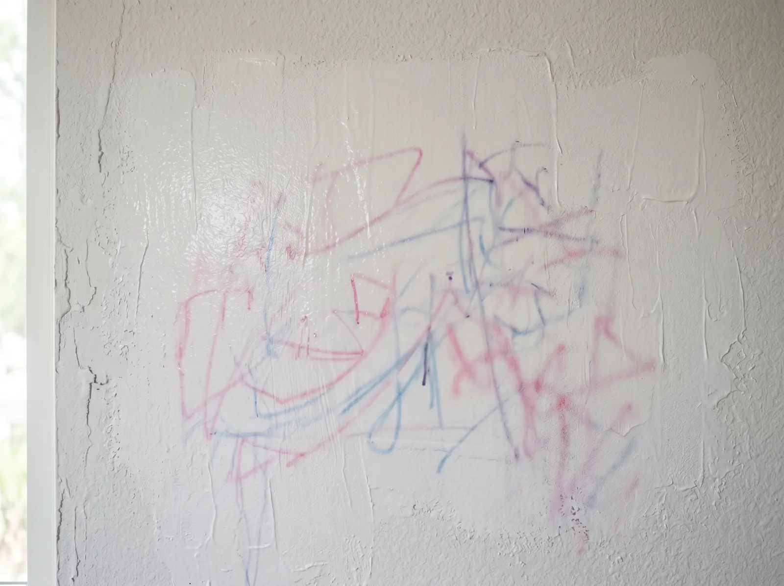 Marker scribbles bleeding back through a single coat of fresh white paint