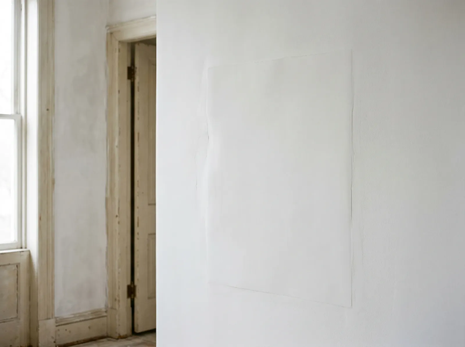 Repaired plaster wall skim-coated and primed, flat and flush where the crack and bulge used to be