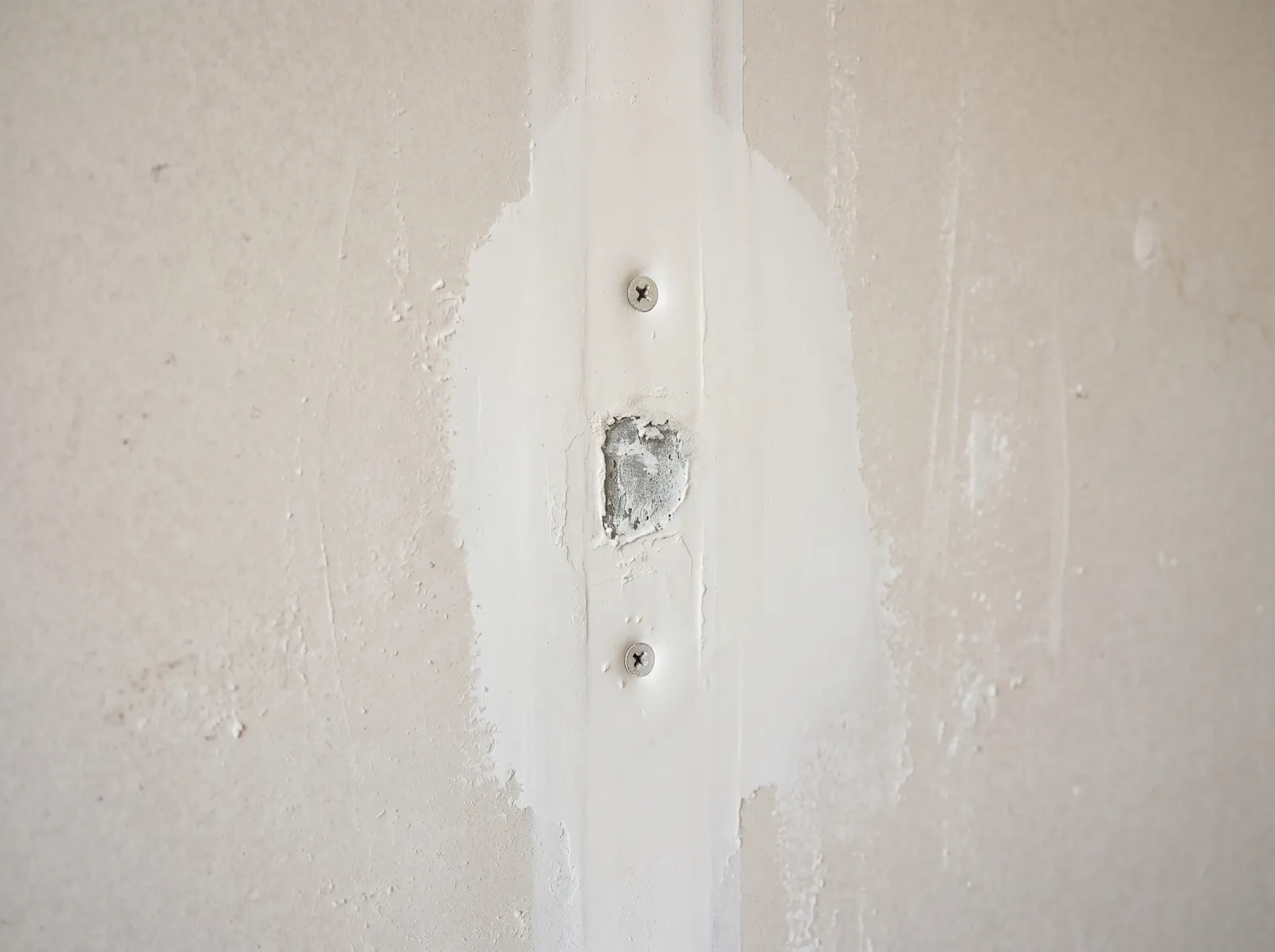 Drywall pop re-screwed above and below the old fastener and skimmed flush with feathered setting compound