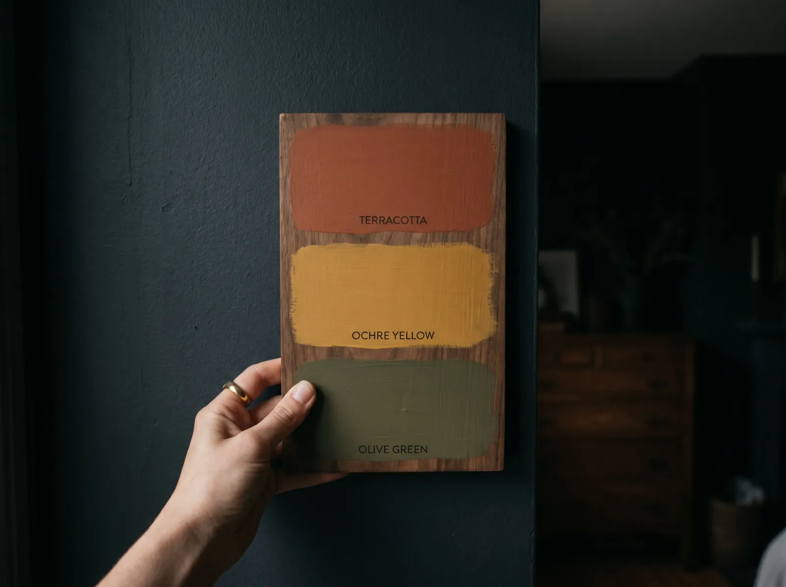 The same sample board held against the shadowed wall, now reading deeper and warmer like the wall itself
