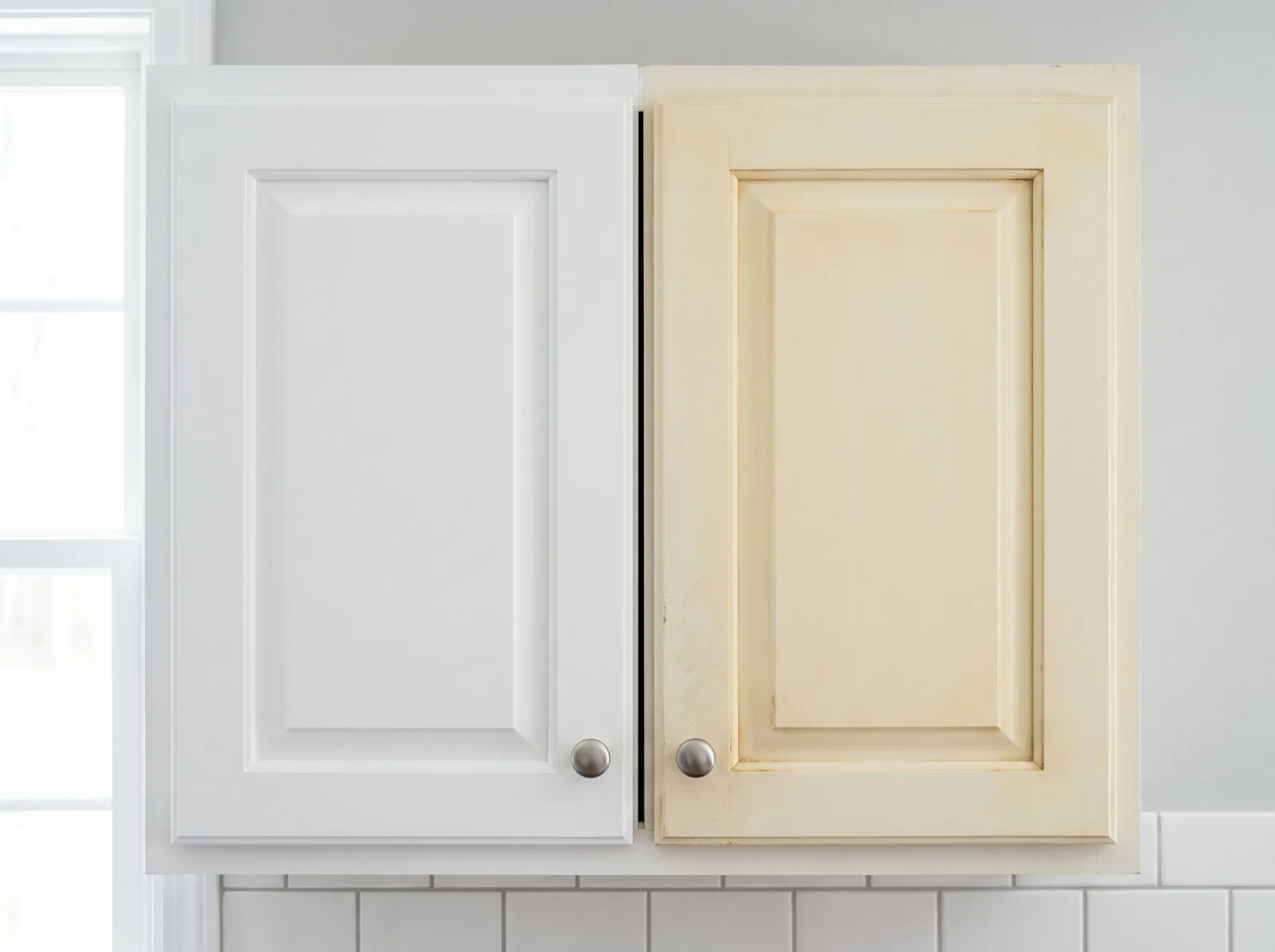 Two white cabinet doors side by side, one bright white and one shifted to warm cream-yellow