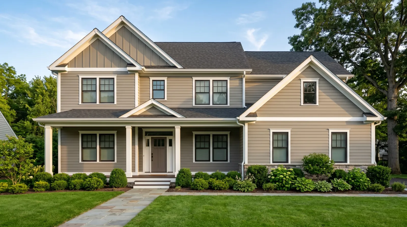 Finished house exterior with even warm-grey siding and white trim in raking afternoon light