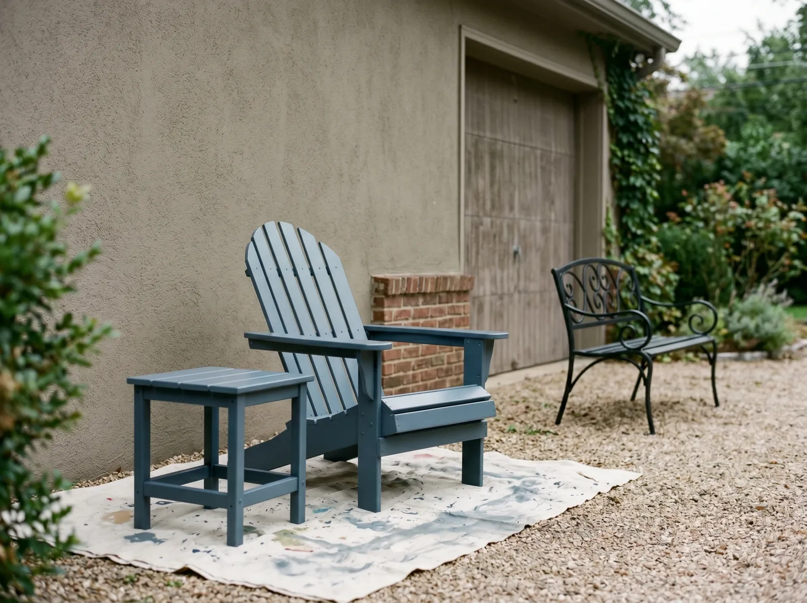 Painted slate-blue chair and table curing in shade beside a black iron bench