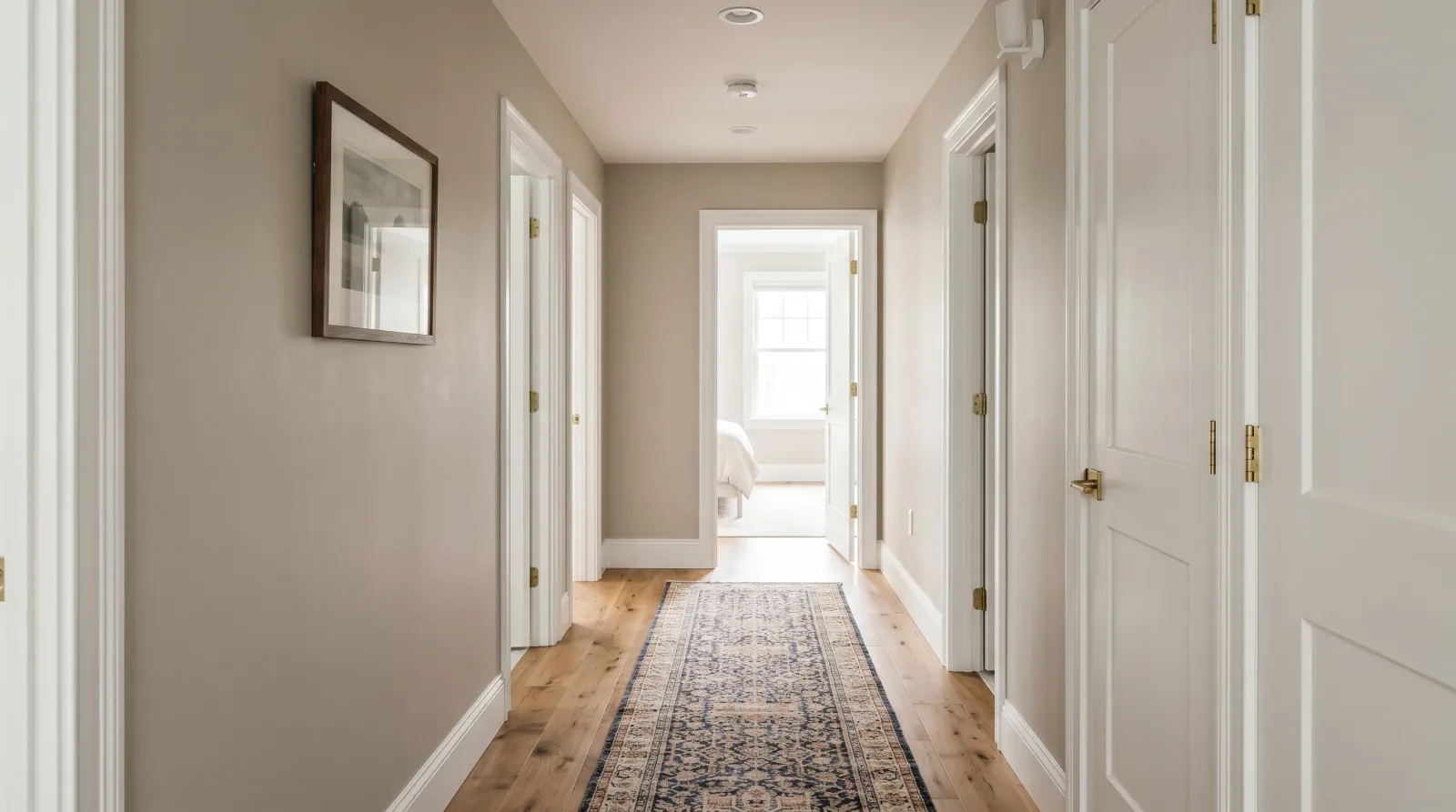 Finished hallway with smooth greige walls, white trim, and pictures rehung