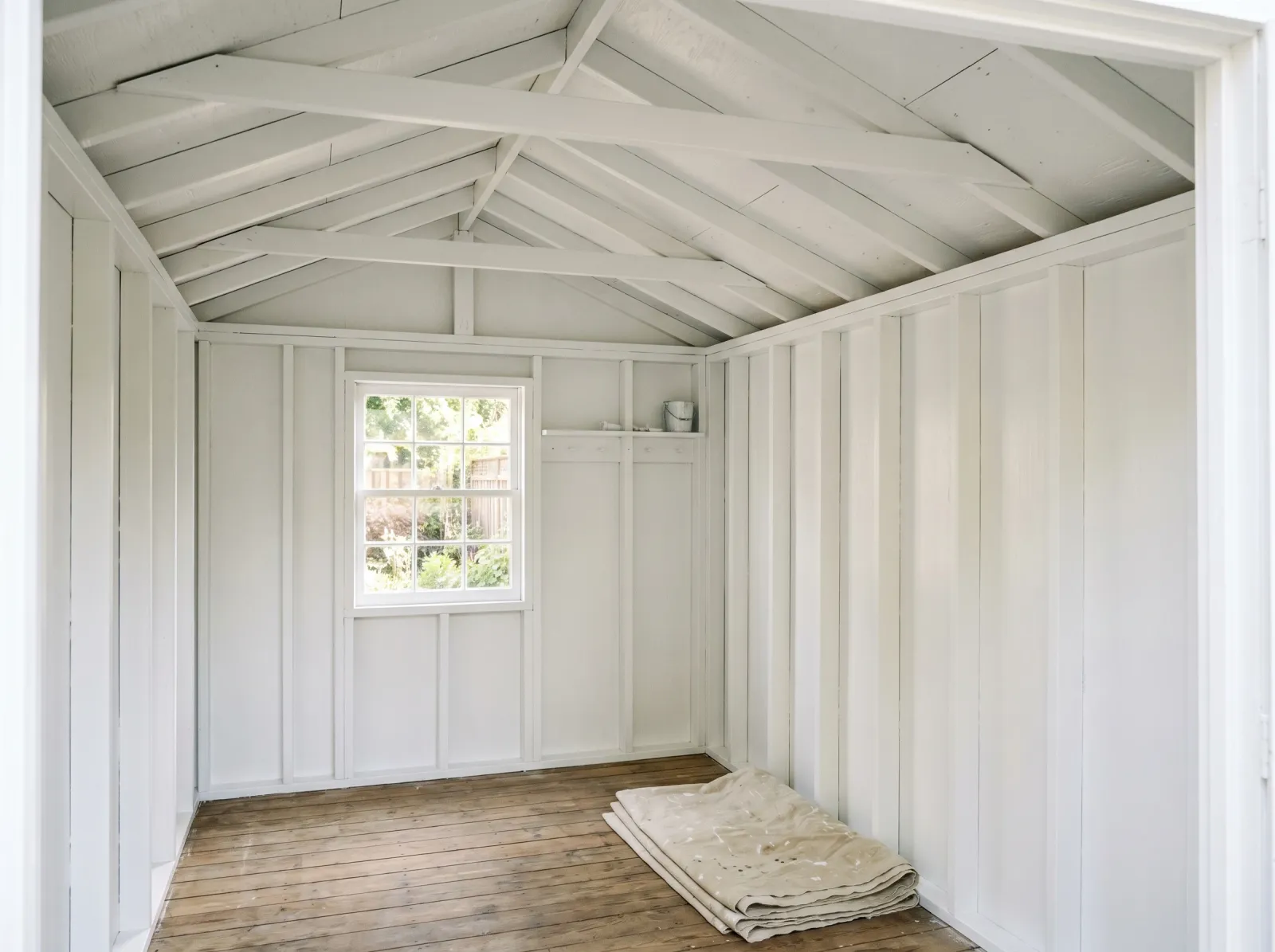 Shed interior with smooth even white second coat on walls and roof sheathing