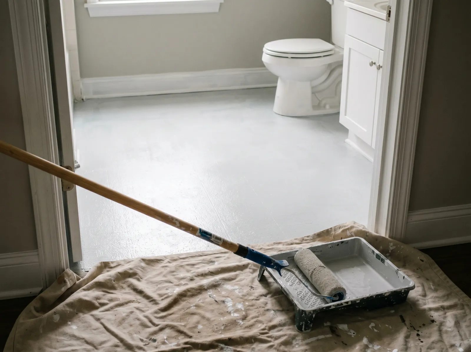 Bathroom linoleum floor coated in one thin coat of grey-white bonding primer