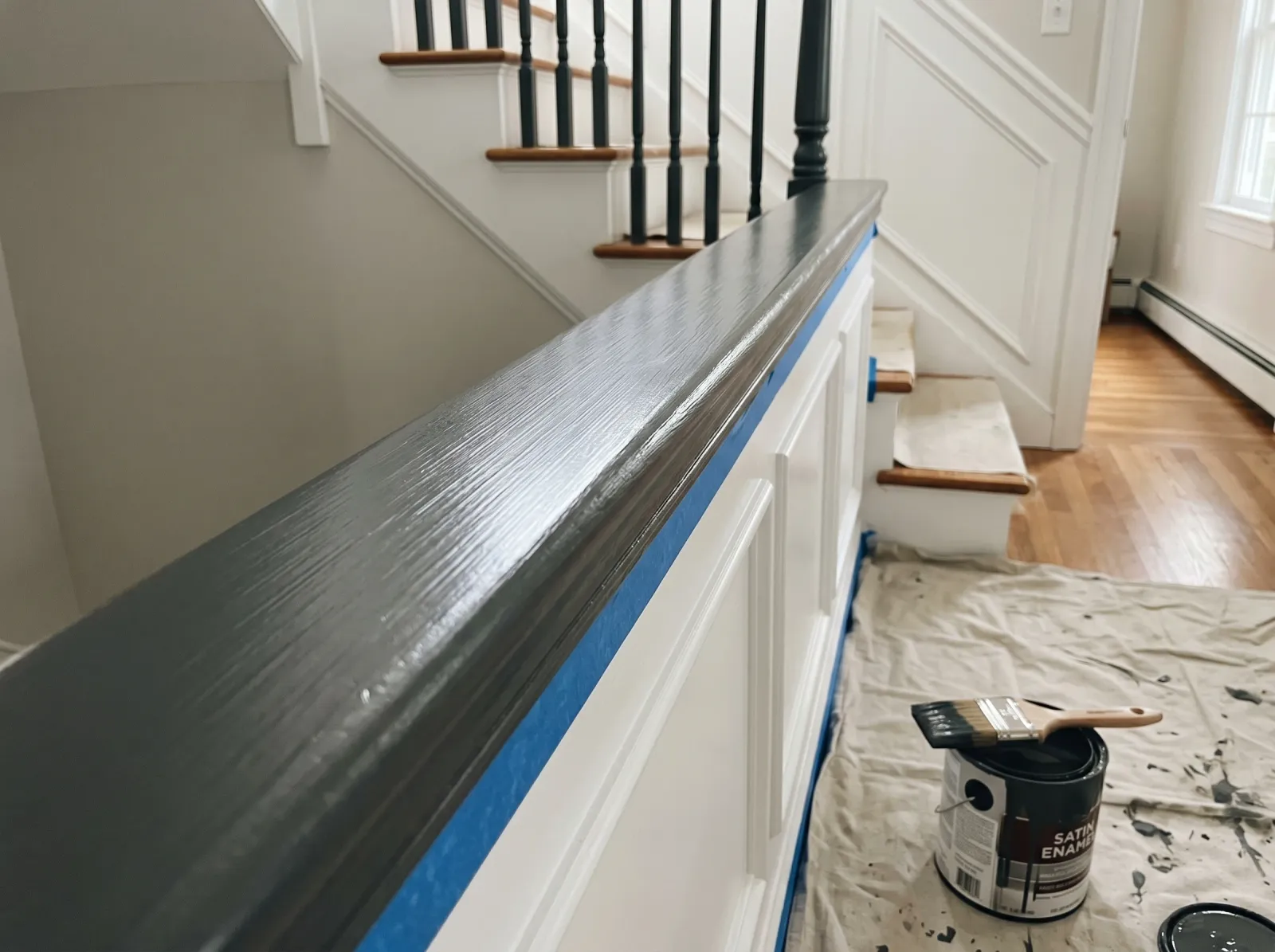 Staircase handrail with first coat of satin dark grey urethane enamel laid in long strokes